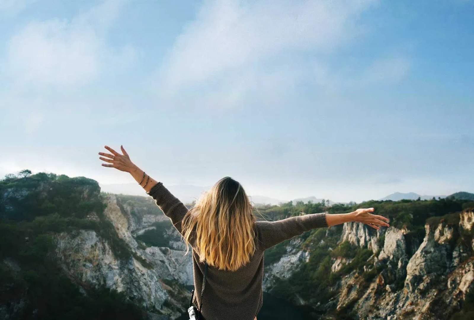 Healthcare traveler standing on a mountain cliff with arms outstretched