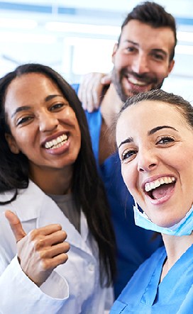 Three healthcare professionals smiling, one giving a thumbs up